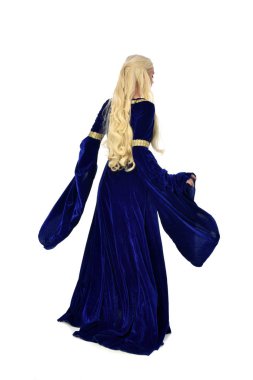 tam uzunlukta bir mavi fantezi Ortaçağ elbisesi giymiş güzel sarışın kadın portresi. Beyaz arka plan üzerinde ayakta poz.