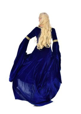 tam uzunlukta bir mavi fantezi Ortaçağ elbisesi giymiş güzel sarışın kadın portresi. Beyaz arka plan üzerinde ayakta poz.