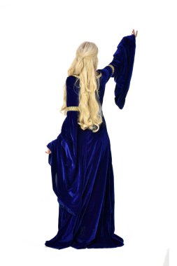 tam uzunlukta bir mavi fantezi Ortaçağ elbisesi giymiş güzel sarışın kadın portresi. Beyaz arka plan üzerinde ayakta poz.