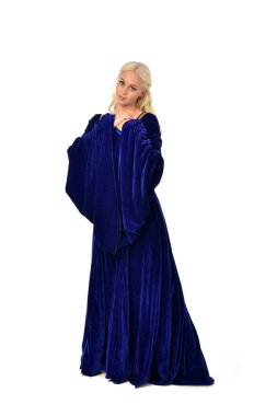 tam uzunlukta bir mavi fantezi Ortaçağ elbisesi giymiş güzel sarışın kadın portresi. Beyaz arka plan üzerinde ayakta poz.