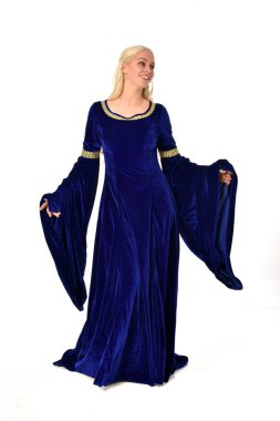 tam uzunlukta bir mavi fantezi Ortaçağ elbisesi giymiş güzel sarışın kadın portresi. Beyaz arka plan üzerinde ayakta poz.