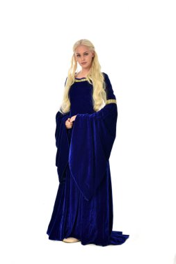 tam uzunlukta bir mavi fantezi Ortaçağ elbisesi giymiş güzel sarışın kadın portresi. Beyaz arka plan üzerinde ayakta poz.