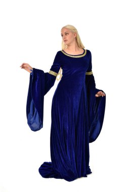 tam uzunlukta bir mavi fantezi Ortaçağ elbisesi giymiş güzel sarışın kadın portresi. Beyaz arka plan üzerinde ayakta poz.