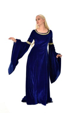 tam uzunlukta bir mavi fantezi Ortaçağ elbisesi giymiş güzel sarışın kadın portresi. Beyaz arka plan üzerinde ayakta poz.