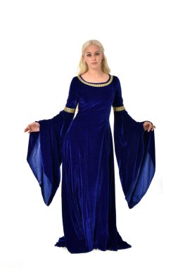 tam uzunlukta bir mavi fantezi Ortaçağ elbisesi giymiş güzel sarışın kadın portresi. Beyaz arka plan üzerinde ayakta poz.