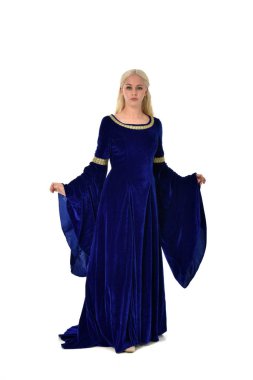 tam uzunlukta bir mavi fantezi Ortaçağ elbisesi giymiş güzel sarışın kadın portresi. Beyaz arka plan üzerinde ayakta poz.