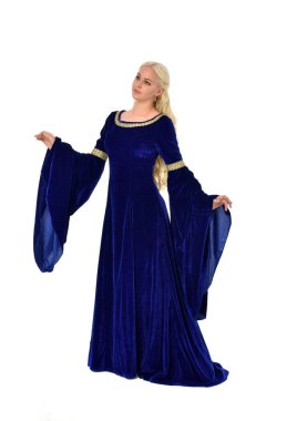 tam uzunlukta bir mavi fantezi Ortaçağ elbisesi giymiş güzel sarışın kadın portresi. Beyaz arka plan üzerinde ayakta poz.