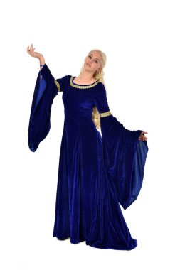 tam uzunlukta bir mavi fantezi Ortaçağ elbisesi giymiş güzel sarışın kadın portresi. Beyaz arka plan üzerinde ayakta poz.