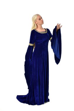 tam uzunlukta bir mavi fantezi Ortaçağ elbisesi giymiş güzel sarışın kadın portresi. Beyaz arka plan üzerinde ayakta poz.