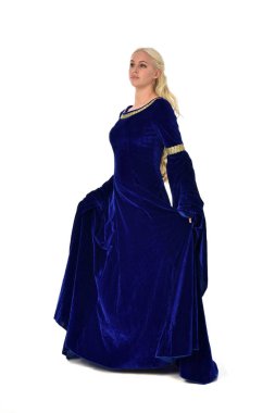 tam uzunlukta bir mavi fantezi Ortaçağ elbisesi giymiş güzel sarışın kadın portresi. Beyaz arka plan üzerinde ayakta poz.