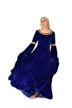 tam uzunlukta bir mavi fantezi Ortaçağ elbisesi giymiş güzel sarışın kadın portresi. Beyaz arka plan üzerinde ayakta poz.