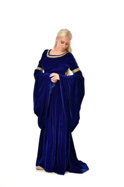 tam uzunlukta bir mavi fantezi Ortaçağ elbisesi giymiş güzel sarışın kadın portresi. Beyaz arka plan üzerinde ayakta poz.