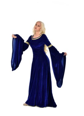 tam uzunlukta bir mavi fantezi Ortaçağ elbisesi giymiş güzel sarışın kadın portresi. Beyaz arka plan üzerinde ayakta poz.