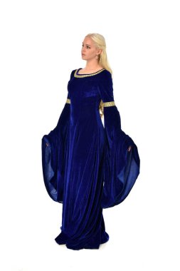 tam uzunlukta bir mavi fantezi Ortaçağ elbisesi giymiş güzel sarışın kadın portresi. Beyaz arka plan üzerinde ayakta poz.