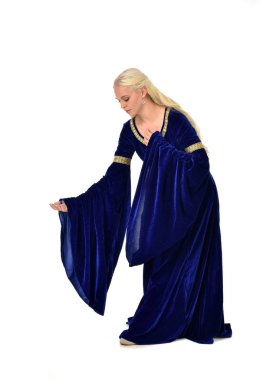 tam uzunlukta bir mavi fantezi Ortaçağ elbisesi giymiş güzel sarışın kadın portresi. Beyaz arka plan üzerinde ayakta poz.