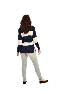 Tam boy kot pantolon ve rahat bir jumper giyen kız portresi. ayakta poz, beyaz stüdyo arka plan üzerinde izole.