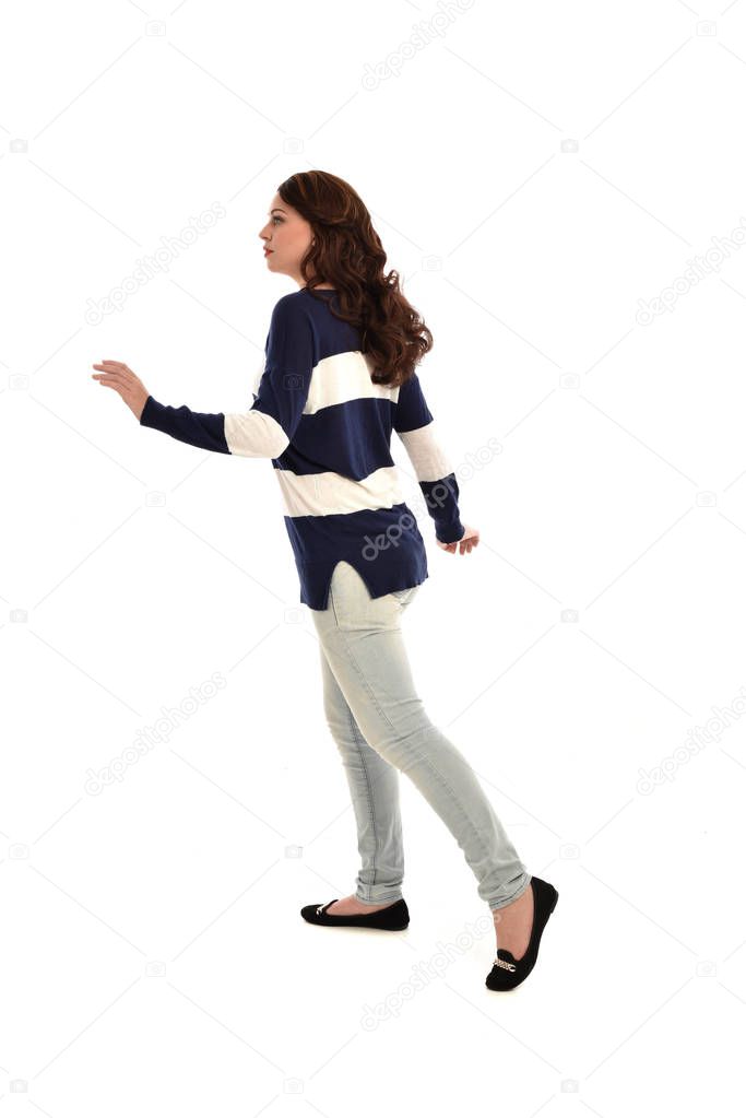 full length portrait of girl wearing jeans and a casual jumper. standing pose, isolated on white studio background.