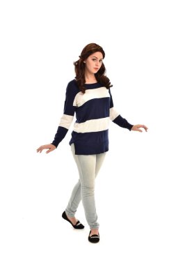 Tam boy çizgili mavi ve beyaz jumper ve kot giyen kız portresi. beyaz stüdyo arka plan üzerinde ayakta poz.