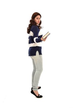 tam uzunlukta bir kitap çizgili mavi ve beyaz jumper ve kot giyen kız portresi. beyaz stüdyo arka plan üzerinde ayakta poz.