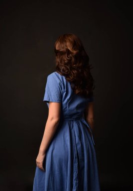 3/4 mavi elbise esmer kadın portresi. geri siyah stüdyo arka plan üzerinde kamera için poz verdi.