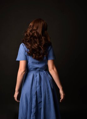 3/4 mavi elbise esmer kadın portresi. geri siyah stüdyo arka plan üzerinde kamera için poz verdi.