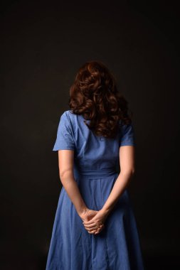 3/4 mavi elbise esmer kadın portresi. geri siyah stüdyo arka plan üzerinde kamera için poz verdi.