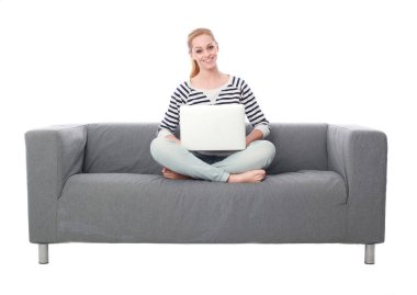 beyaz stüdyo arka plan üzerinde izole bir gri kanepede oturan kız portresi tam uzunlukta.