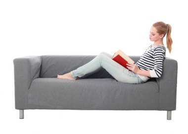 beyaz stüdyo arka plan üzerinde izole bir gri kanepede oturan kız portresi tam uzunlukta.