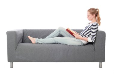 beyaz stüdyo arka plan üzerinde izole bir gri kanepede oturan kız portresi tam uzunlukta.