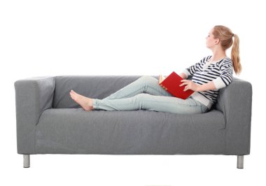 beyaz stüdyo arka plan üzerinde izole bir gri kanepede oturan kız portresi tam uzunlukta.