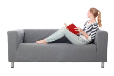 beyaz stüdyo arka plan üzerinde izole bir gri kanepede oturan kız portresi tam uzunlukta.