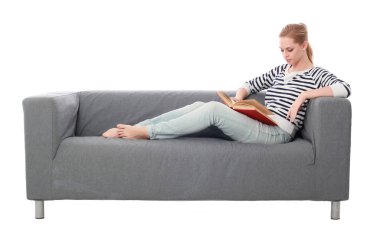 beyaz stüdyo arka plan üzerinde izole bir gri kanepede oturan kız portresi tam uzunlukta.