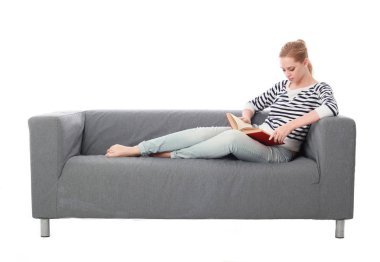 beyaz stüdyo arka plan üzerinde izole bir gri kanepede oturan kız portresi tam uzunlukta.