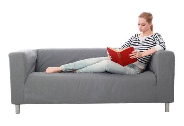 beyaz stüdyo arka plan üzerinde izole bir gri kanepede oturan kız portresi tam uzunlukta.