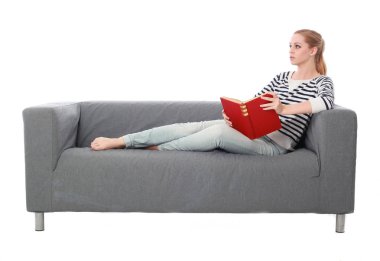 beyaz stüdyo arka plan üzerinde izole bir gri kanepede oturan kız portresi tam uzunlukta.