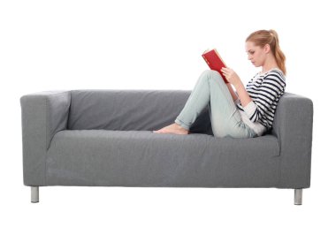 beyaz stüdyo arka plan üzerinde izole bir gri kanepede oturan kız portresi tam uzunlukta.