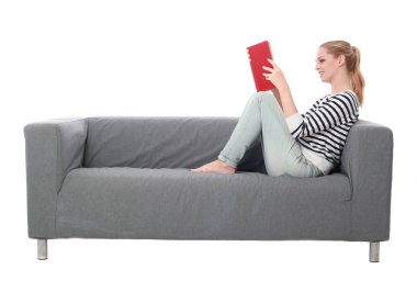 beyaz stüdyo arka plan üzerinde izole bir gri kanepede oturan kız portresi tam uzunlukta.