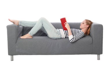 beyaz stüdyo arka plan üzerinde izole bir gri kanepede oturan kız portresi tam uzunlukta.