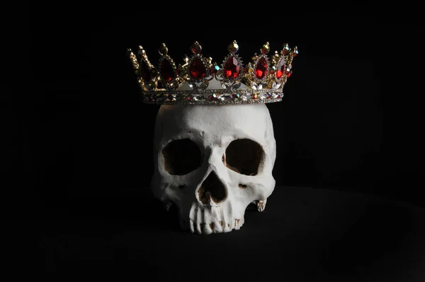 在黑色背景下 一个戴着红色和金色宝石王冠的人头骨关闭 — 图库照片
