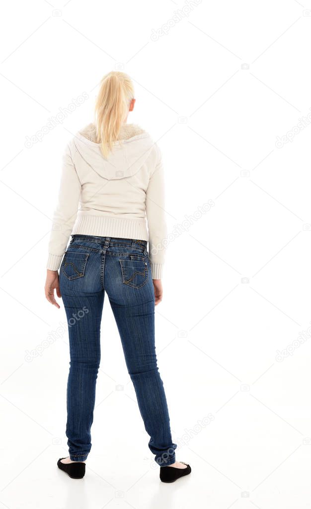 full length portrait of blonde girl wearing  white jumper and jeans. standing pose on white studio background