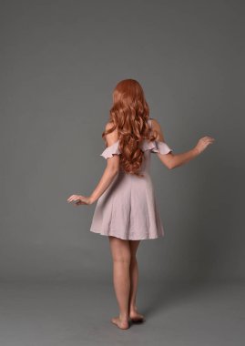 tam uzunlukta pembe yazlık elbise giyen kız portresi. gri studio arka plan üzerinde ayakta poz