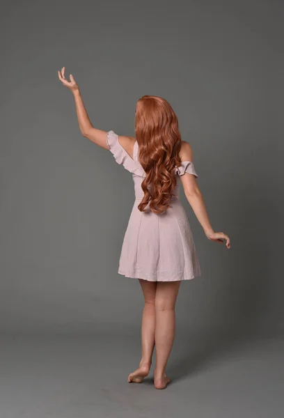 ピンクの夏のドレスを着ている少女の完全な長さの肖像画 灰色のスタジオの背景に立ちポーズ — ストック写真