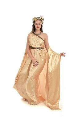 Tam boy poz ayakta altın Yunan elbisesi giymiş esmer kadın portresi. beyaz stüdyo arka plan üzerinde izole.