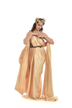 Tam boy poz ayakta altın Yunan elbisesi giymiş esmer kadın portresi. beyaz stüdyo arka plan üzerinde izole.