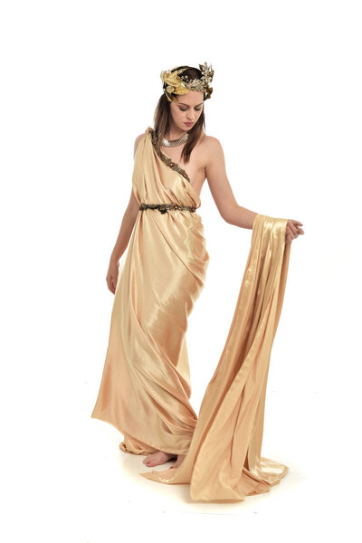 full length portrait of brunette woman wearing gold grecian gown, standing pose. isolated on white studio background.