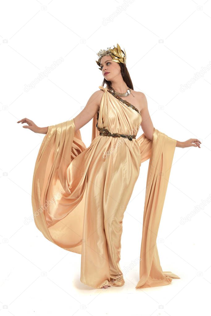 full length portrait of brunette woman wearing gold grecian gown, standing pose. isolated on white studio background.