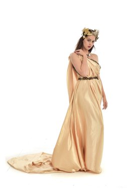 Tam boy poz ayakta altın Yunan elbisesi giymiş esmer kadın portresi. beyaz stüdyo arka plan üzerinde izole.