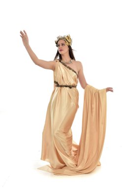 Tam boy poz ayakta altın Yunan elbisesi giymiş esmer kadın portresi. beyaz stüdyo arka plan üzerinde izole.
