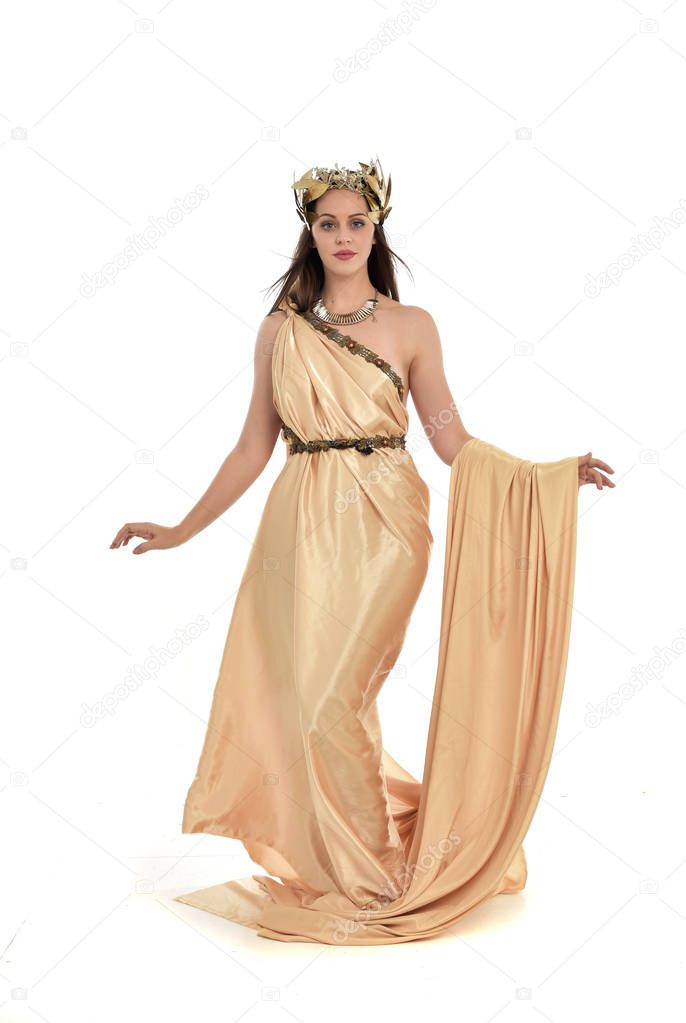 full length portrait of brunette woman wearing gold grecian gown, standing pose. isolated on white studio background.