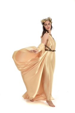 Tam boy poz ayakta altın Yunan elbisesi giymiş esmer kadın portresi. beyaz stüdyo arka plan üzerinde izole.